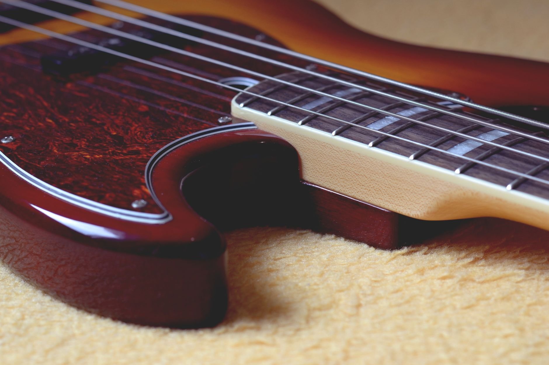 Detailed close-up of a tobacco burst bass guitar featuring intricate neck and body details