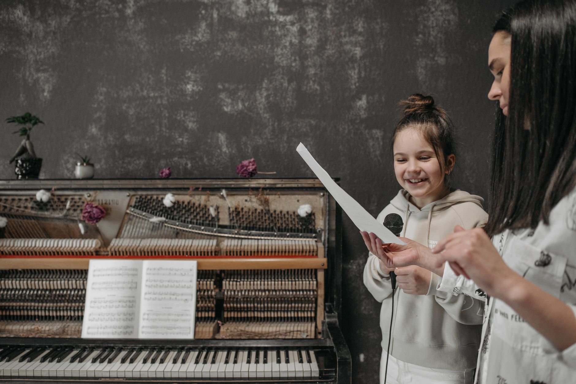 A young girl learning piano with a teacher in a cozy, vintage-styled room