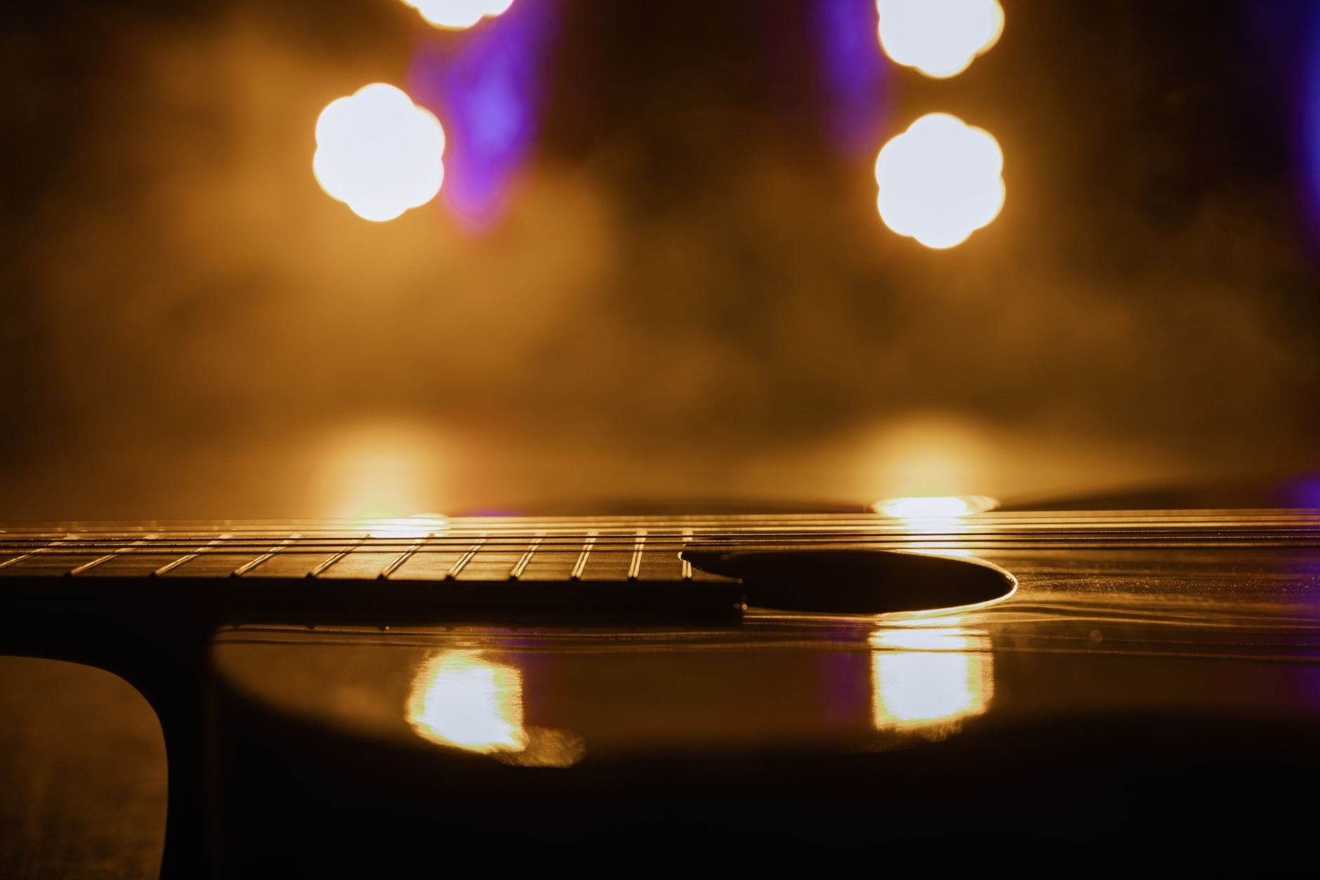 Close-up view of an acoustic guitar in warm, dramatic lighting